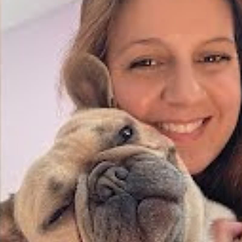 Kristen smiling cheek to cheek with one of her French bulldogs.